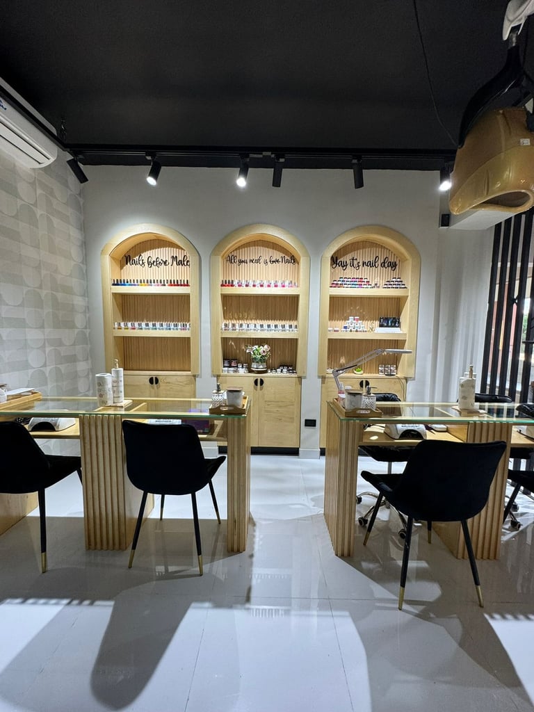 Modern nail salon interior with three arched wooden display shelves, glass counters, black chairs, and track lighting