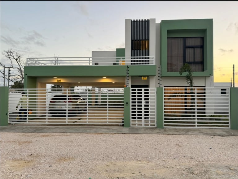 Modern two-story house with green and white horizontal stripe gate and facade, sunset sky