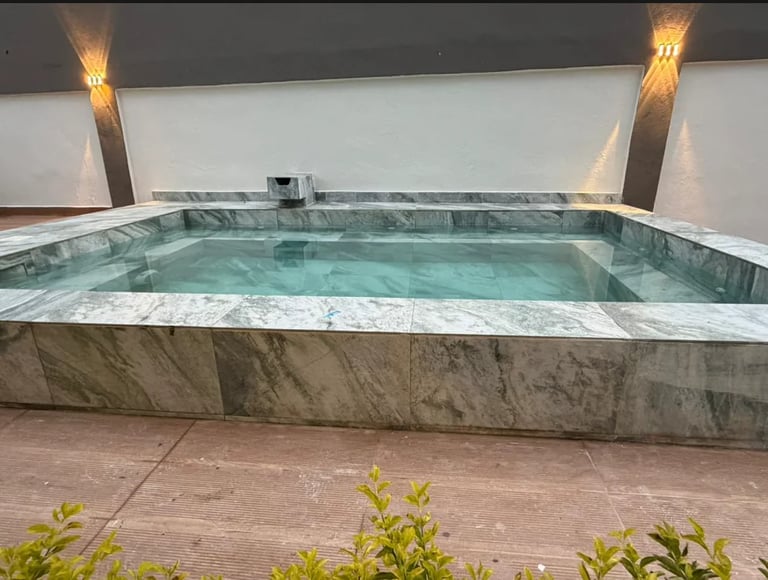 Jacuzzi exterior con agua turquesa y mármol